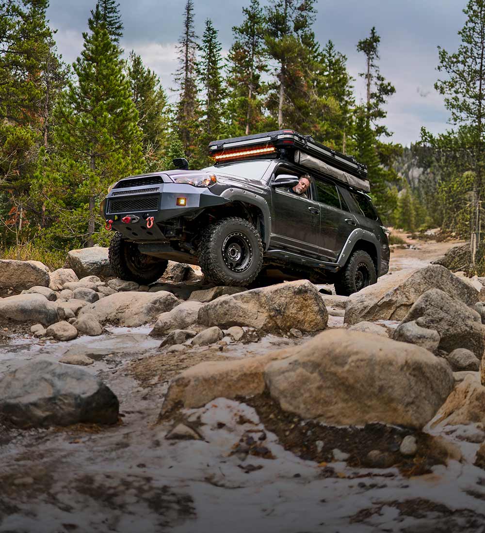Offroad-Fahrzeug, das in der Nähe eines Baches über Felsen fährt
