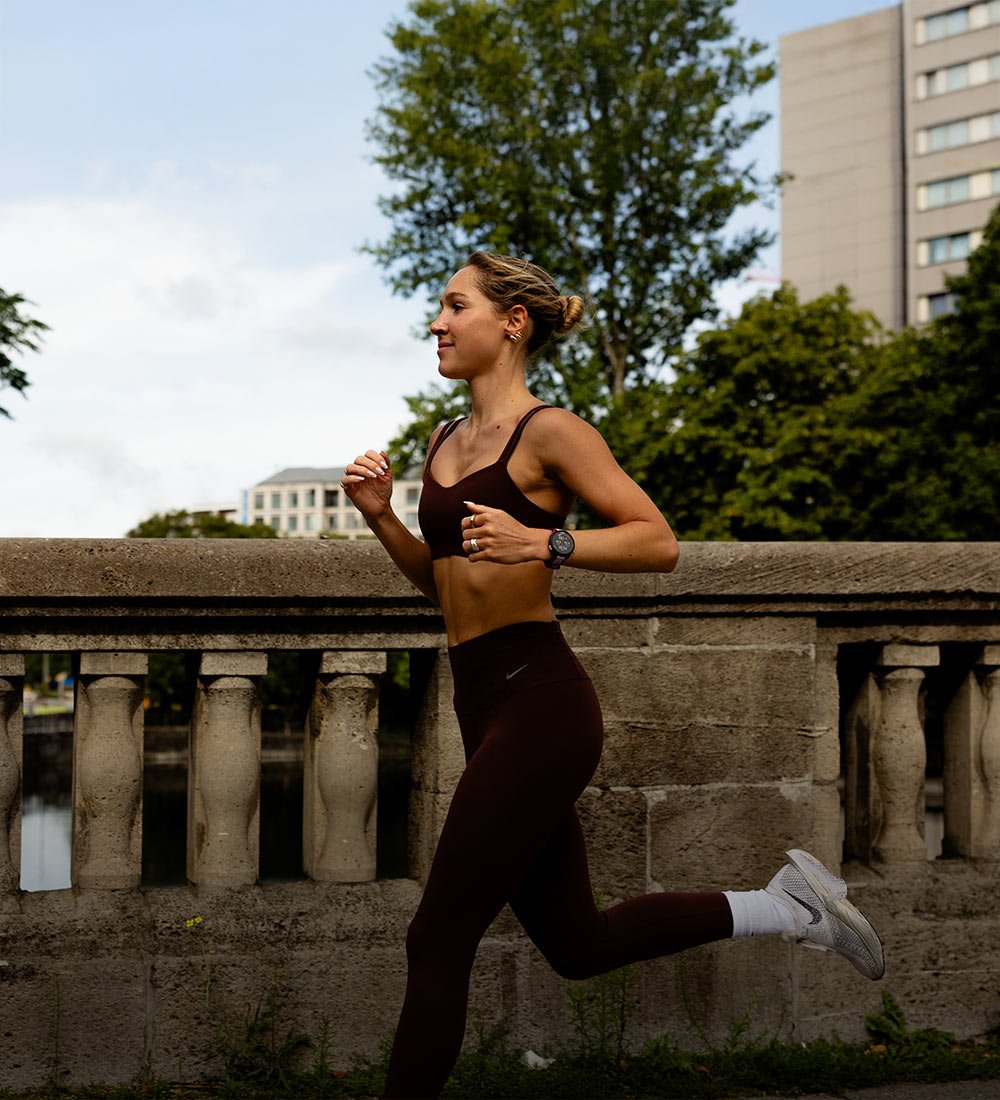 Frau, die in der Stadt über eine Steinbrücke joggt